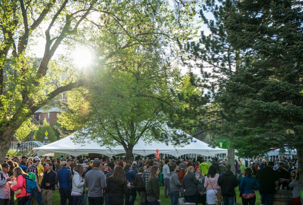 Crowd gathering outside around tents serving beverages and food.