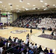 A basketball court with fans in the stands and players on the court.